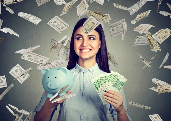 Woman with piggy bank and euro cash under dollar money rain — Stock Photo, Image