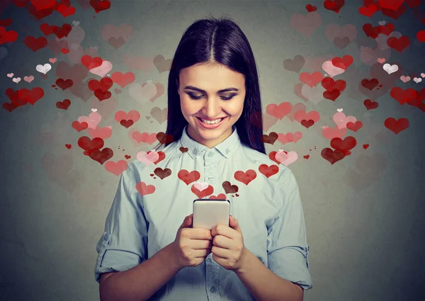 Happy woman sending love message on mobile phone hearts flying away — Stock Photo, Image