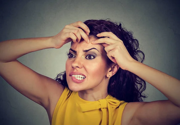 Woman looking in a mirror squeezing acne or blackhead on her face — Stock Photo, Image