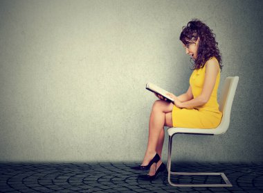 Genç kadın bir sandalyede oturan bir kitap okuma 