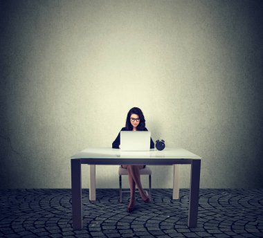 Dizüstü bilgisayar kullanan bir masada oturan işkadını 