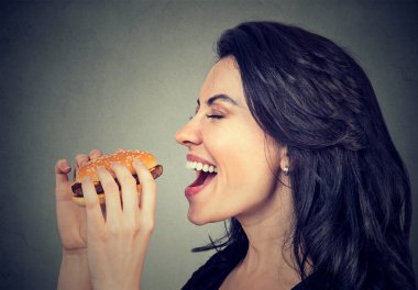 Yan profil genç kadın lezzetli hamburger yemek