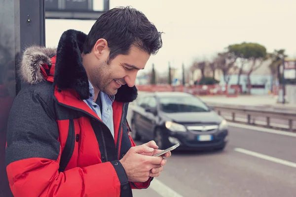 Hombre llamando a un taxi con una aplicación de teléfono inteligente de pie a lo largo de la carretera — Foto de Stock