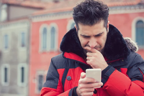 Verwirrter verärgerter Mann blickt auf sein im Freien stehendes Handy — Stockfoto