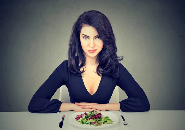 Attraktiv ung kvinna sitter vid bord redo att äta grön sallad — Stockfoto