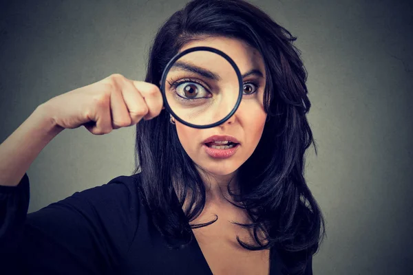 Surprised woman looking through magnifying glass — Stock Photo, Image