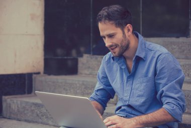 Mutlu adam açık havada gülümseyen onun dizüstü bilgisayar kullanan 