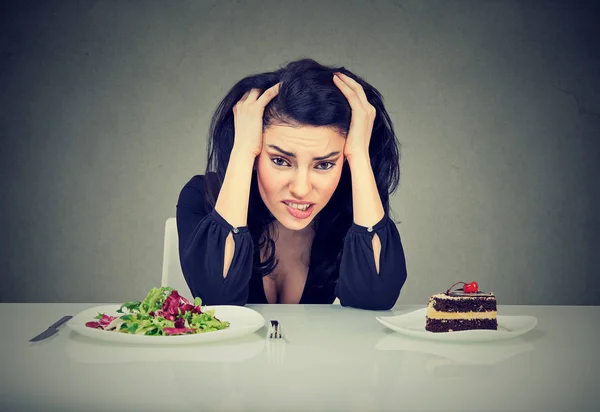 Femme fatiguée des restrictions alimentaires décidant de manger des aliments sains ou un gâteau dont elle a soif — Photo