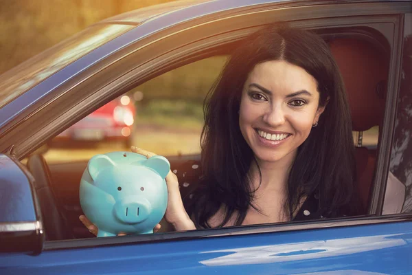 Mulher feliz sentada dentro de seu carro com banco porquinho — Fotografia de Stock