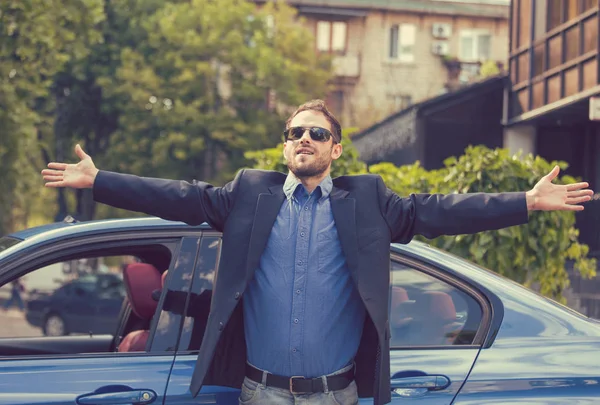 Sukces człowieka stojącego przy jego nowy samochód, ciesząc się w letni dzień — Zdjęcie stockowe