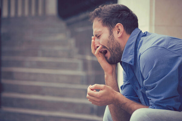 sorrowful crying man sitting on steps outdoors 