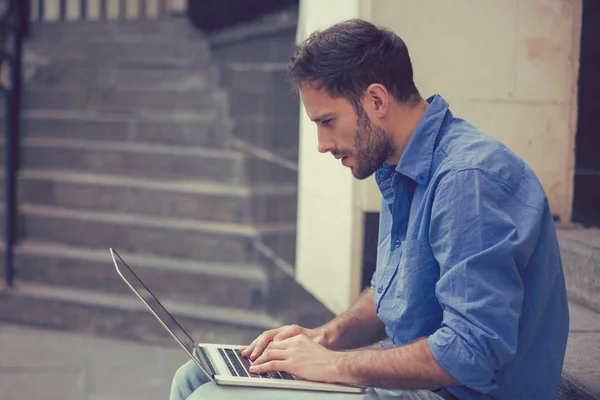 Homem trabalhando em laptop ao ar livre sentado em passos fora de seu escritório — Fotografia de Stock