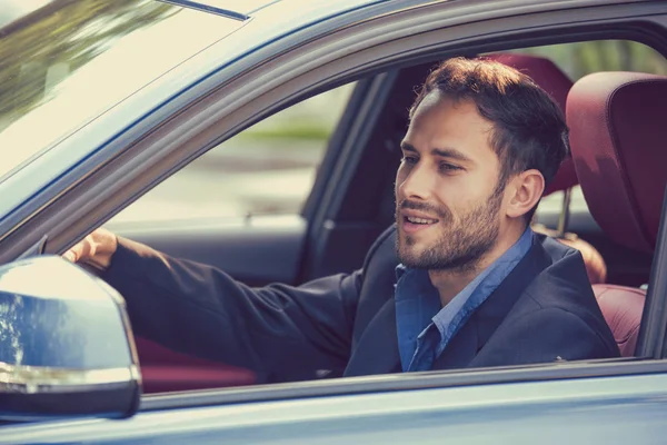 Счастливый мужчина-водитель улыбается за рулем спортивного синего автомобиля, глядя в боковое зеркало — стоковое фото