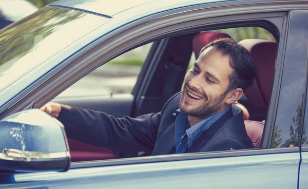 Счастливый мужчина-водитель улыбается за рулем спортивного синего автомобиля, глядя в боковое зеркало — стоковое фото