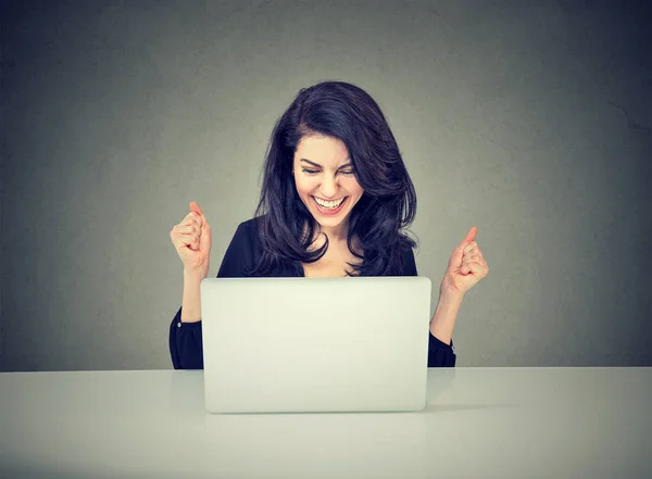 Young businesswoman sitting with her laptop in the office celebrating success Stock Image