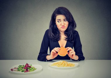 Abur cubur vs sağlıklı gıda. Sebze salatası seyir çizburger ile tereddüt kadın 