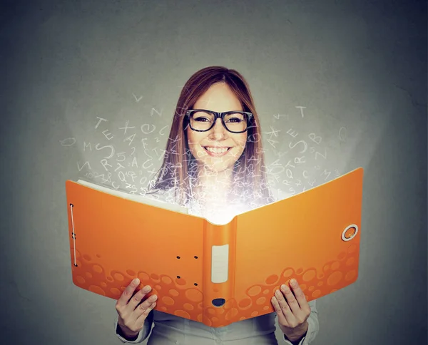 Mulher sorridente lendo um livro com letras voando para longe — Fotografia de Stock