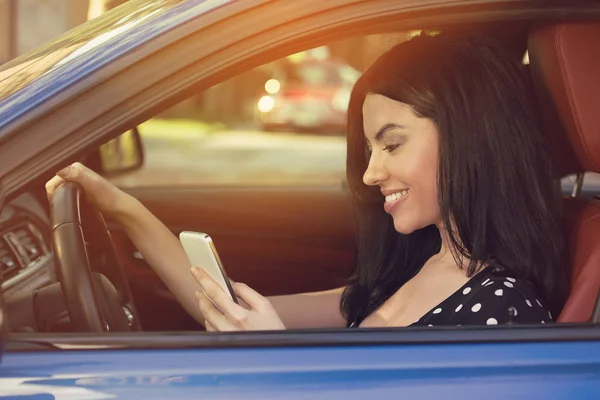 Mujer sonriente enviando un mensaje de texto mientras conduce — Foto de Stock