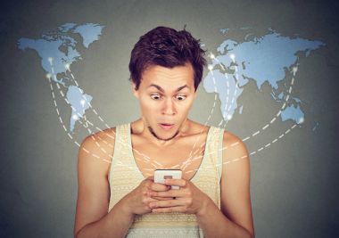 Shocked man looking at smart phone with world map on background  clipart