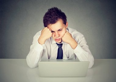 Aşağı bakıyor dizüstü bilgisayar ile masa başında oturan overworked sıkılmış adam 