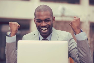 Mutlu başarılı adam dizüstü bilgisayar ile şirket ofisi dışında başarı kutluyor