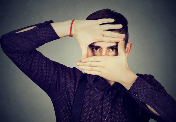 Νεαρός άνδρας που κρυφοκοιτάζουν μέσα από τα χέρια του τα δάχτυλα — Φωτογραφία Αρχείου