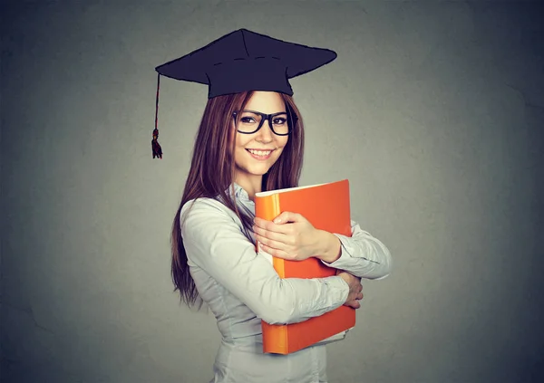 Graduado estudante mulher em cap vestido com pasta olhando para a câmera — Fotografia de Stock