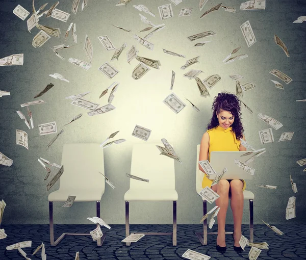 Vrouw die werkt op een laptop geld verdienen. Het ondernemer onder dollar regen. — Stockfoto