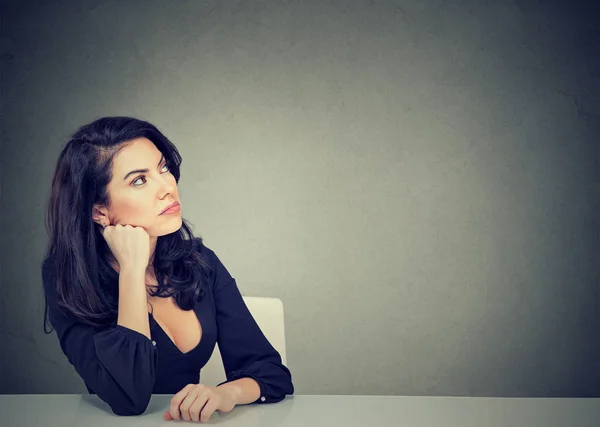 Мыслящая деловая женщина сидит за столом — стоковое фото