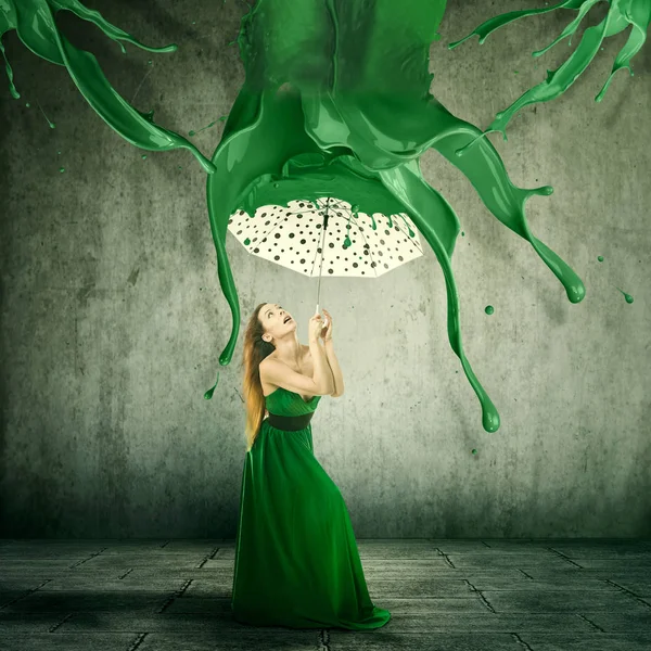 Elegant woman using an umbrella to shelter from color splashes falling down — Stock Photo, Image