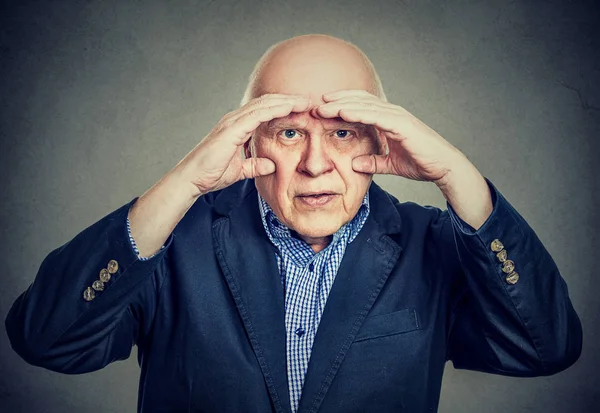 Geërgerd oudere man op zoek via handen als verrekijker heeft visie problemen — Stockfoto