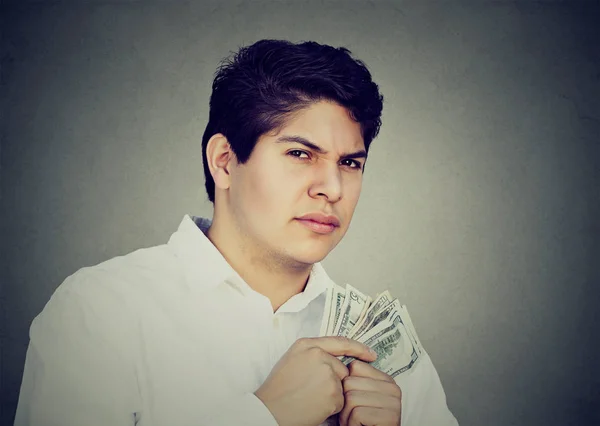 Greedy suspicious man holding money dollar bills in hand