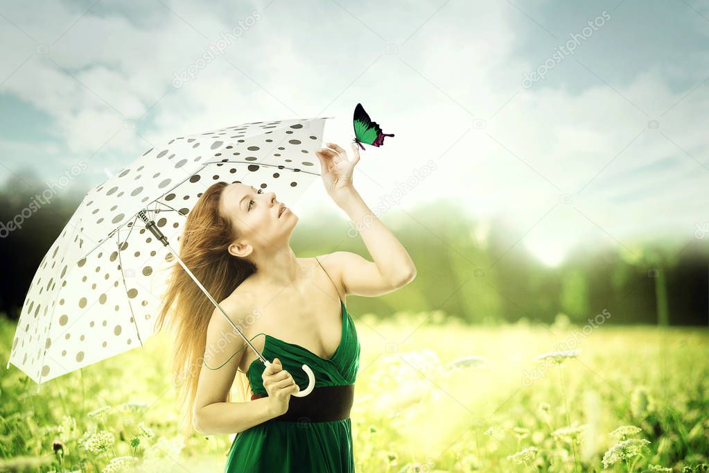 woman with umbrella walking though a park playing with a butterfly  