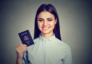 Çekici genç mutlu kadın portre gri duvar arka plan üzerinde izole ABD pasaportu ile. Olumlu insan duyguları ifade yüz. Göçmenlik seyahat kavramı
