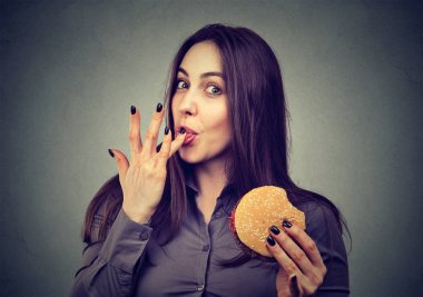 Fast food benim favorim. Genç kadın tadı zevk bir hamburger yemek 