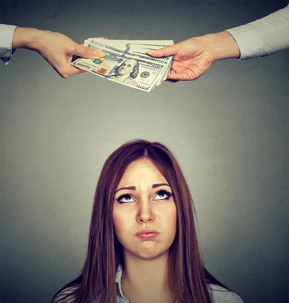 Worried sad woman looking up at two hands exchanging money — Stock Photo, Image