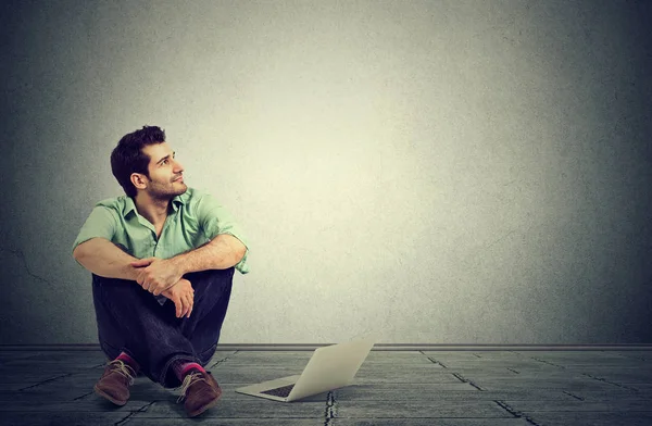 Man with laptop computer sitting on a floor planning daydreaming — Stock Photo, Image