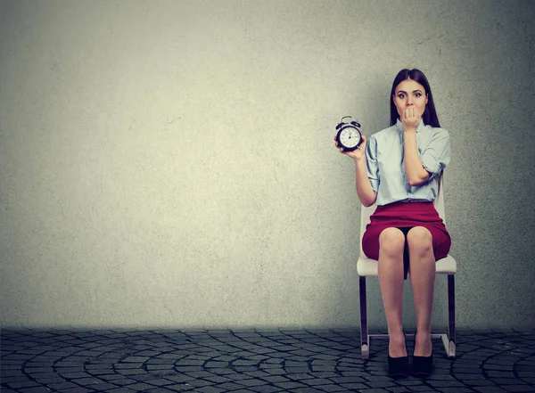 Anxious woman with alarm clock waiting for an interview — Stock Photo, Image