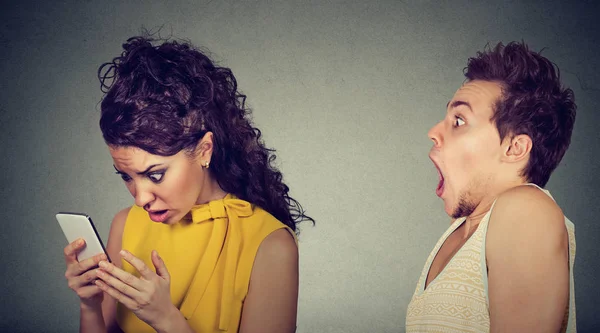 Geschockter Mann schaut verärgerte Freundin an, die sein Handy ausspioniert — Stockfoto