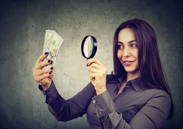 女人看着一百美元的钞票，通过放大镜 — 图库照片