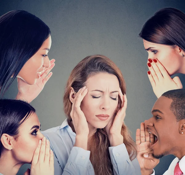 Group of people whispering gossip to a stressed woman suffering from headache — Stock Photo, Image