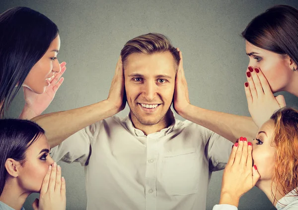Four women whispering gossip to a man who covers ears ignoring all surrounding noise