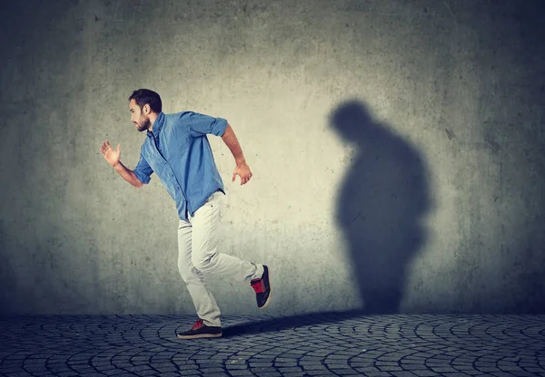Homem fugindo de sua triste sombra gorda sombria na parede — Fotografia de Stock