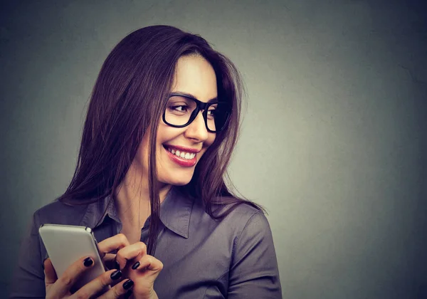 Vacker kvinna med hjälp av smart telefon tittar bort skrattar — Stockfoto