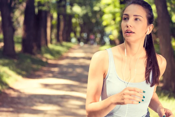 Sportliche Frau joggt im Park im Sonnenaufgangslicht — Stockfoto