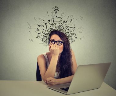 woman with thoughtful expression sitting at a desk with laptop with arrows and symbols coming out of head clipart