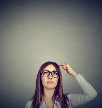 Düşünceli ifade gri duvar arka plan üzerinde ararken kadınla