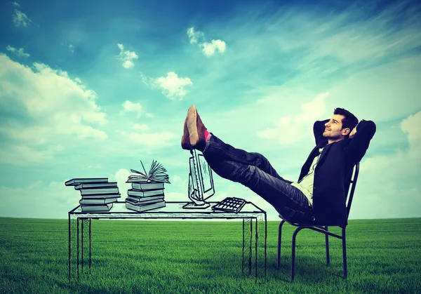 Бизнесмен отдыхает за рабочим столом на свежем воздухе посреди зеленого луга — стоковое фото