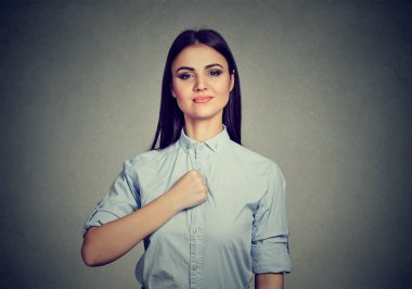 Gri duvar arka plan üzerinde izole kendine güvenen genç kadın