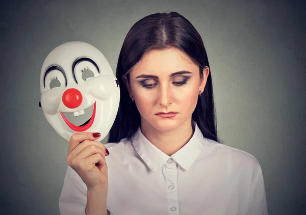 Сумна жінка знімає маску клоуна, що виражає щастя — стокове фото